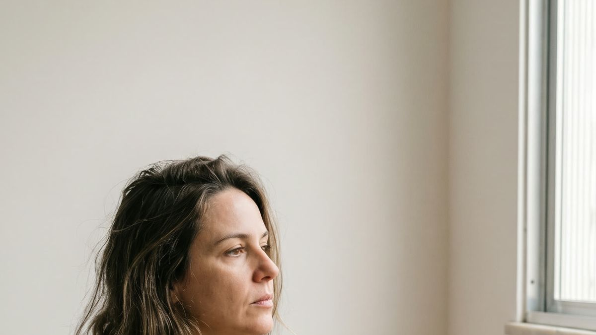 Mulher sentada perto da janela segurando uma xícara
